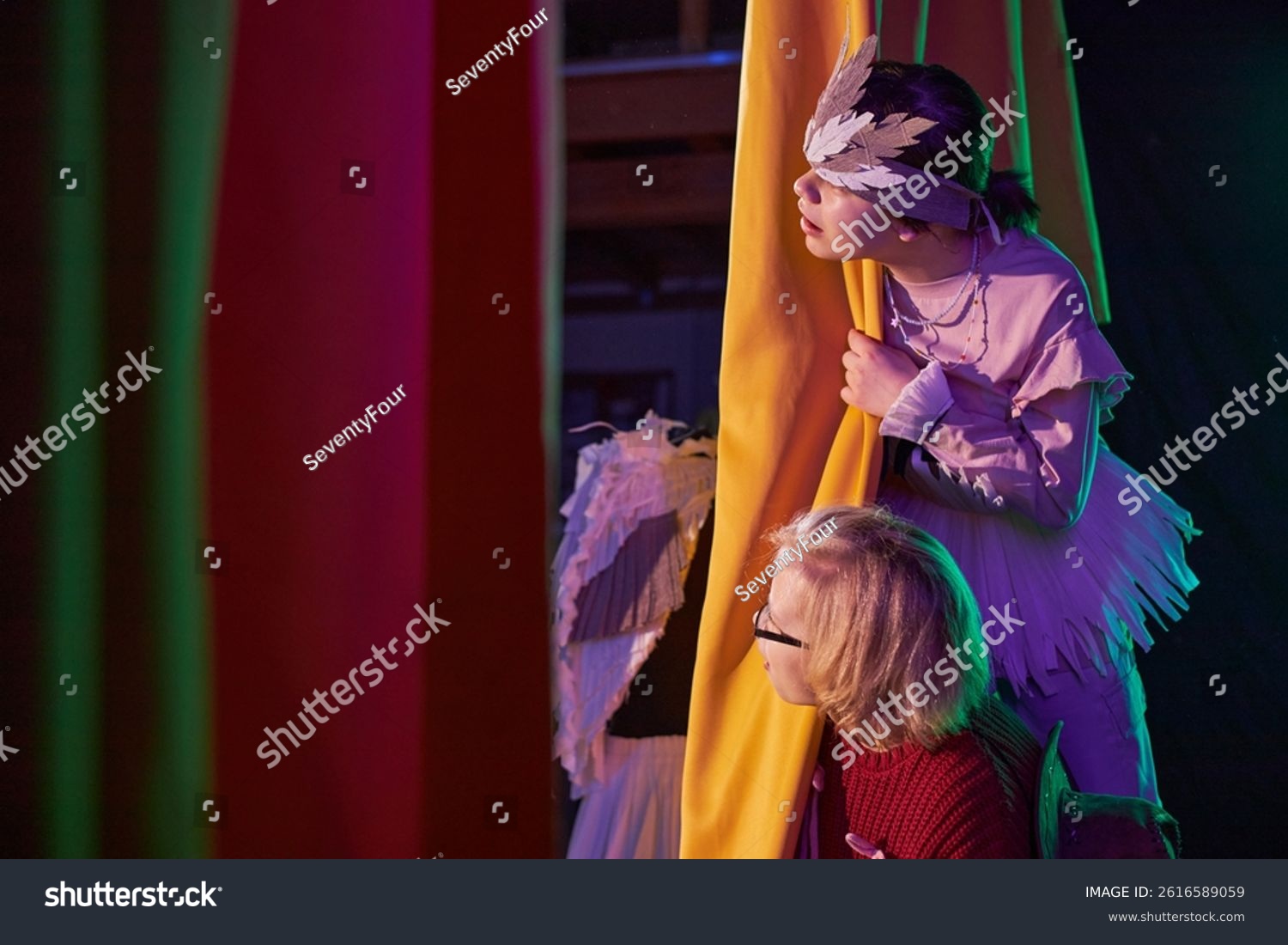 stock-photo-side-view-of-two-young-girls-peeking-from-behind-yellow-curtains-waiting-in-anticipation-to-go-on-2616589059
